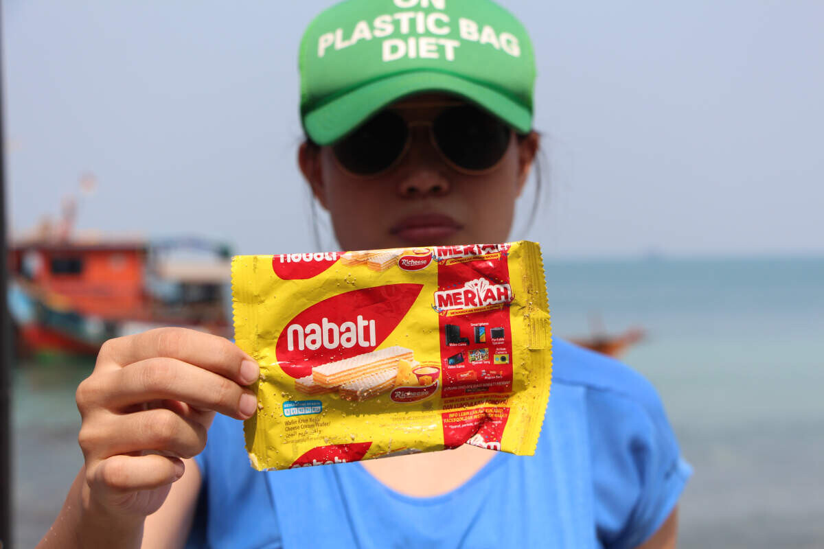 Tiza Mafira holding single-use plastic wrapper - effects of plastic on environment - Fruit-Powered